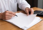 Person reviewing tax documents thoughtfully at a desk
